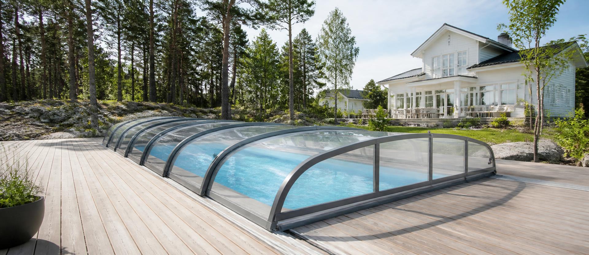 Pooltak i aluminium och polykarbonat över pool med turkost vatten en ljus sommardag