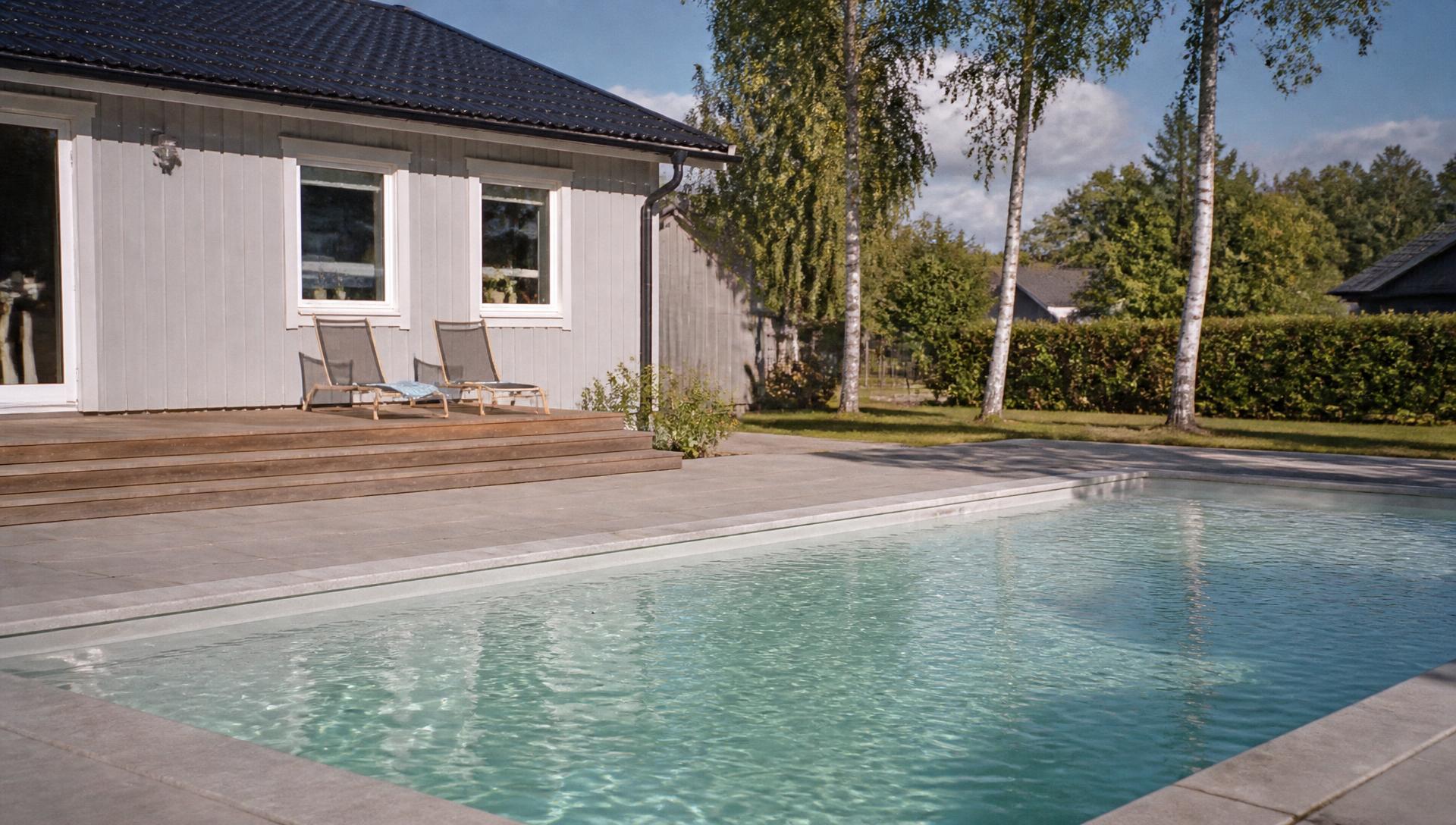 Pool med klart turkost vatten vid en modern skandinavisk villa en ljus sommardag