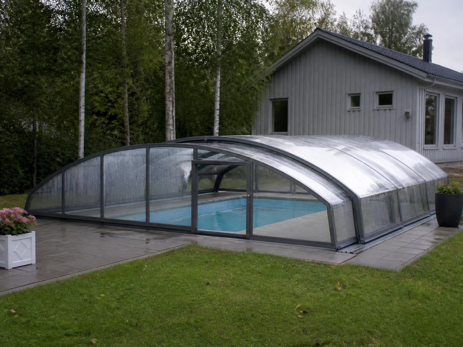 Skjutbart pooltak i glas över en pool i en skandinavisk trädgård